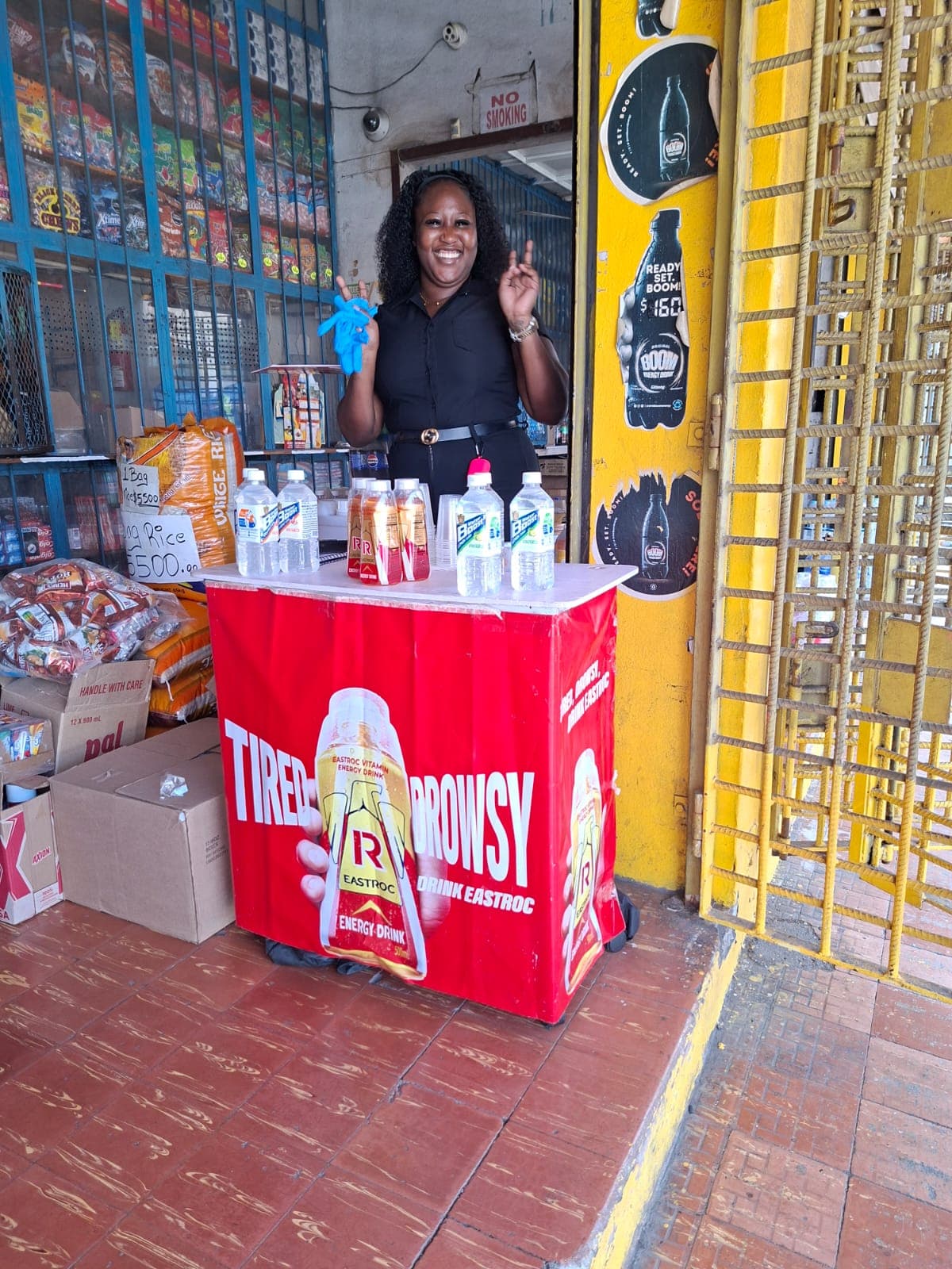 Brand ambassador welcoming shoppers at an Eastroc and Water Boost sampling station.