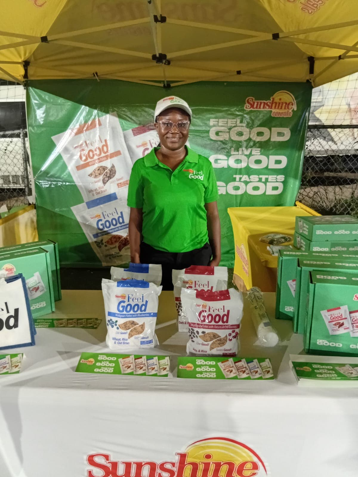 Brand ambassador at a Sunshine Feel Good outdoor activation booth with product samples.
