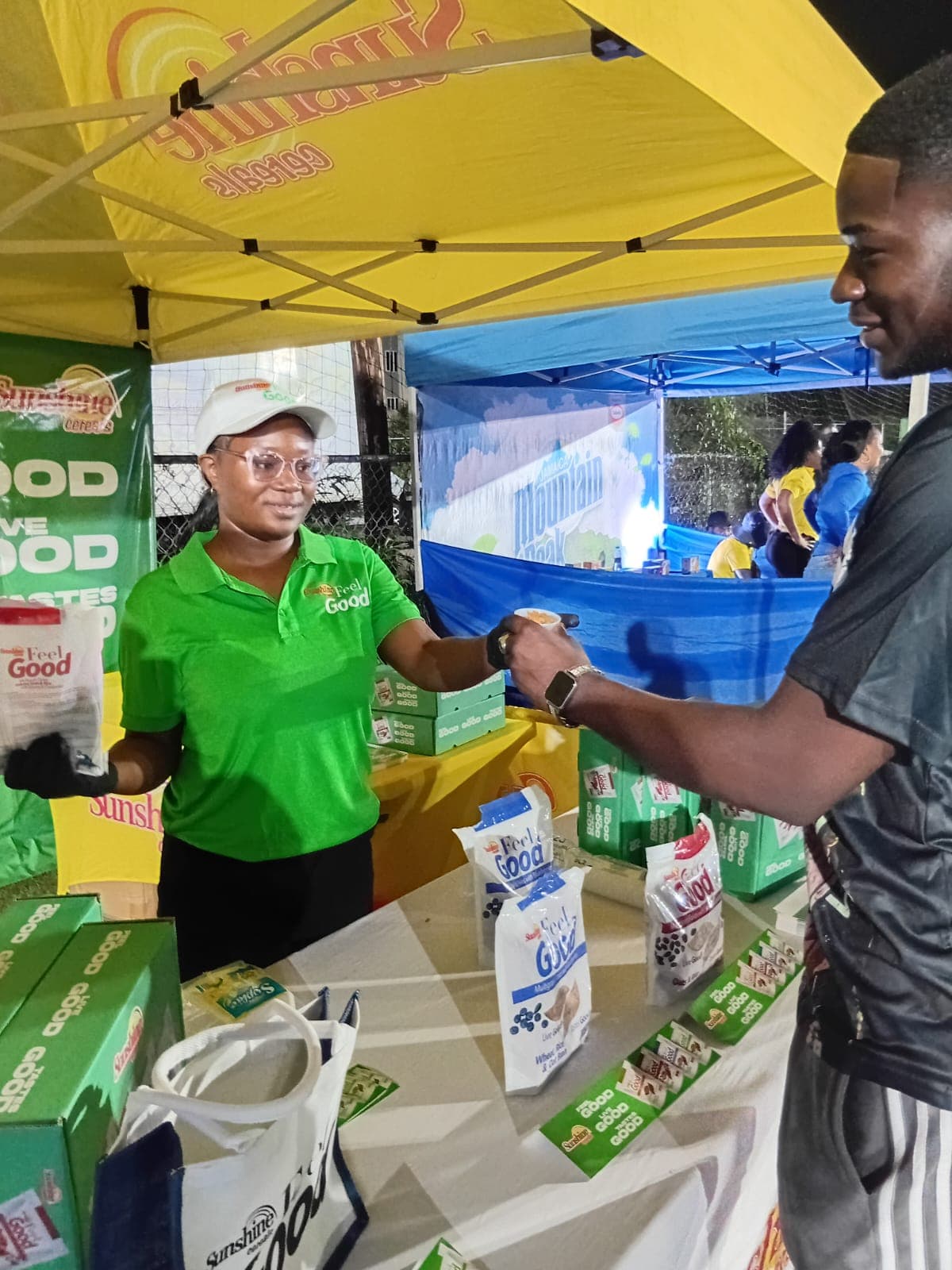 Brand ambassador handing a Feel Good sample to a visitor at an outdoor activation.