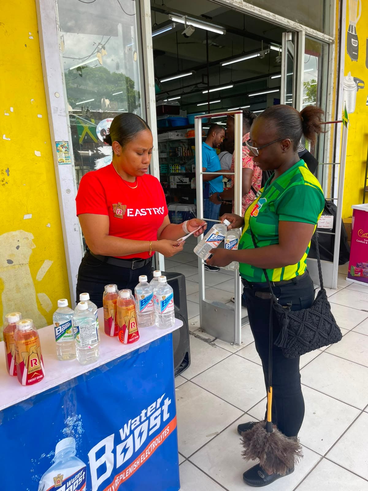 Brand ambassador assisting a customer at a Water Boost product sampling display.