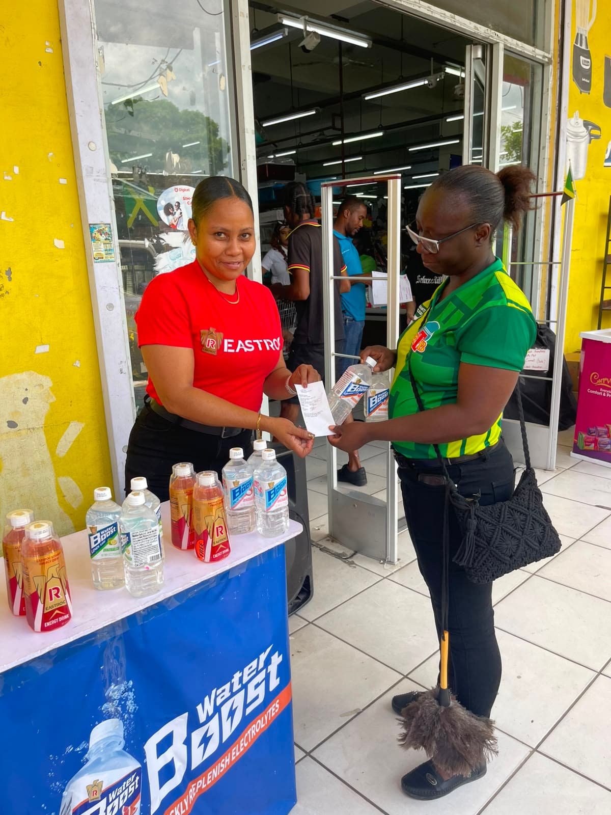 Brand ambassador completing a customer handoff at a Water Boost activation table.